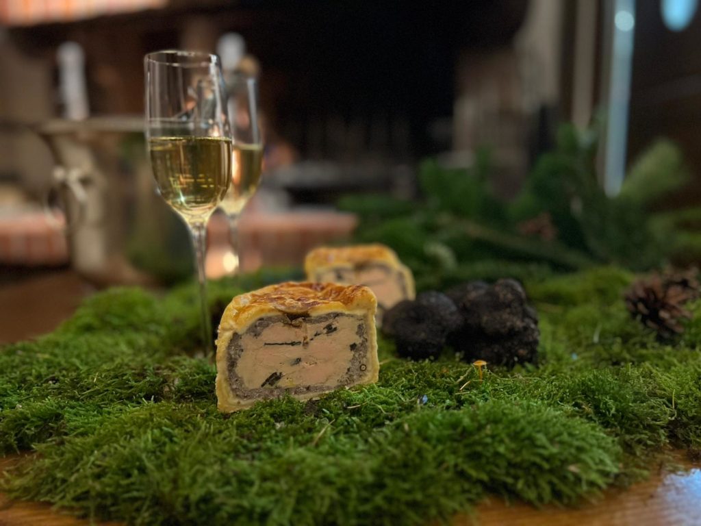 Vue de coupe d'un pâté de foie gras Maréchal des Contades avec des truffes noire et deux flutes de champagne