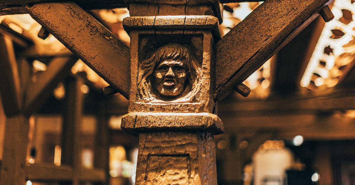 Poutre en bois massif sculptée avec le visage d'une personne tirant la langue. Détail de l'intérieur du restaurant Thierry Schwartz
